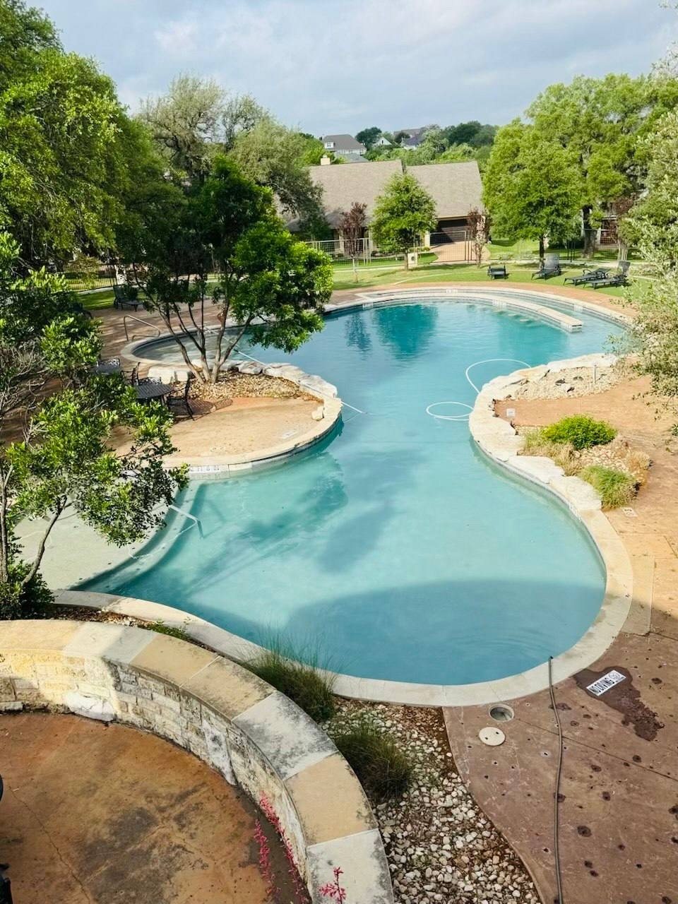 Large residential community pool surrounded by trees and shared outdoor areas
