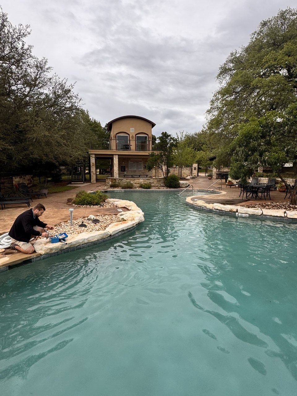 Belle Pools technician checking equipment beside a pool